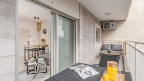Un balcon avec une table, un canapé et une porte-fenêtre coulissante donnant sur une pièce.