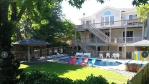 Ein zweistöckiges Gebäude mit Poolbereich, einschließlich Liegestühlen und einer überdachten Lounge.