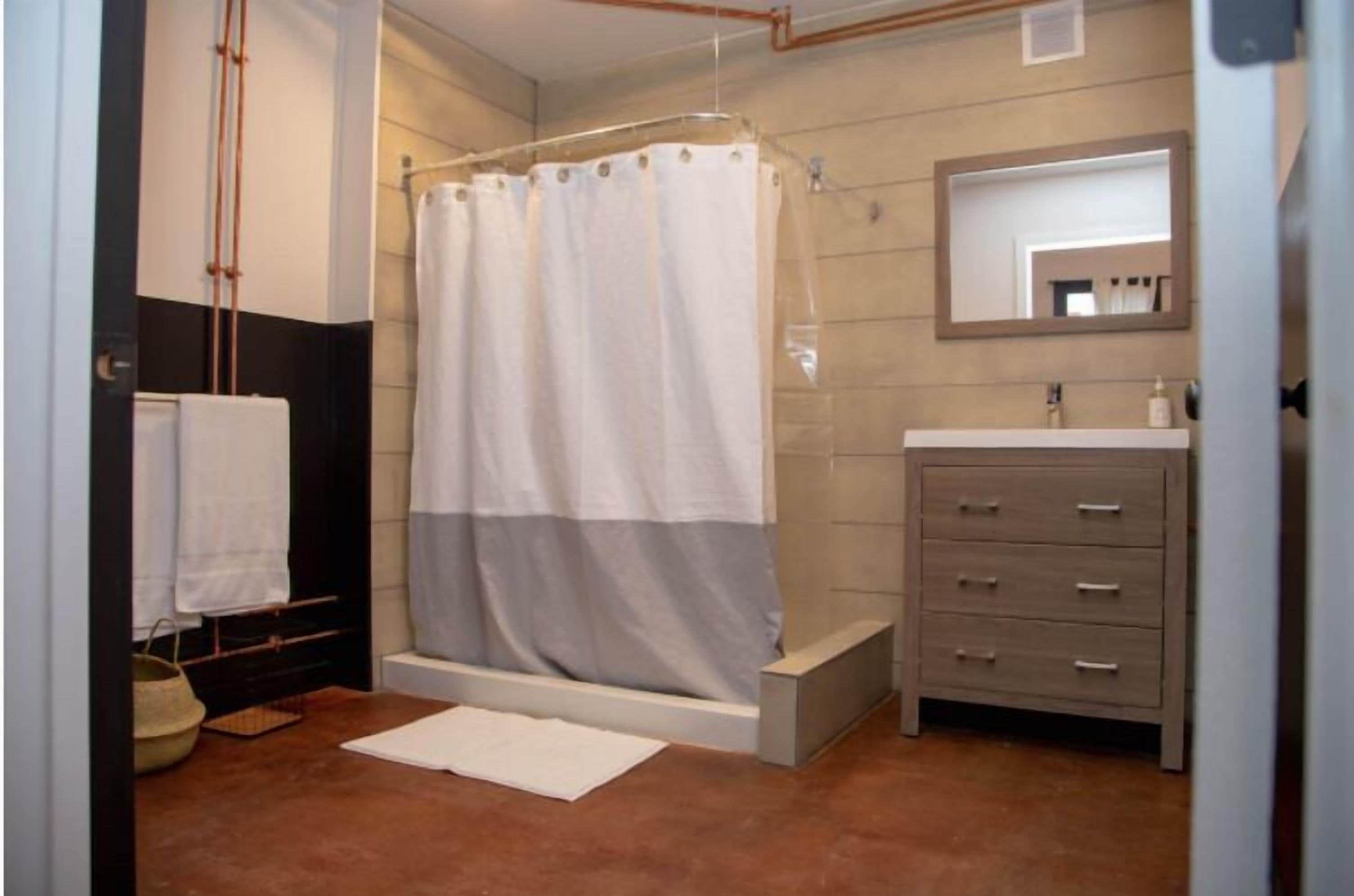 A bathroom with a shower, a sink, and a mirror.