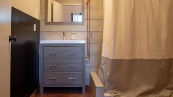 A bathroom with a grey vanity, a mirror, and a shower curtain.