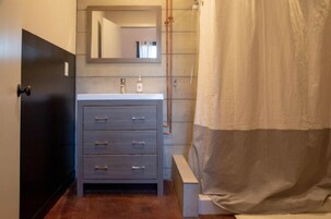 A bathroom with a grey vanity, a mirror, and a shower curtain.