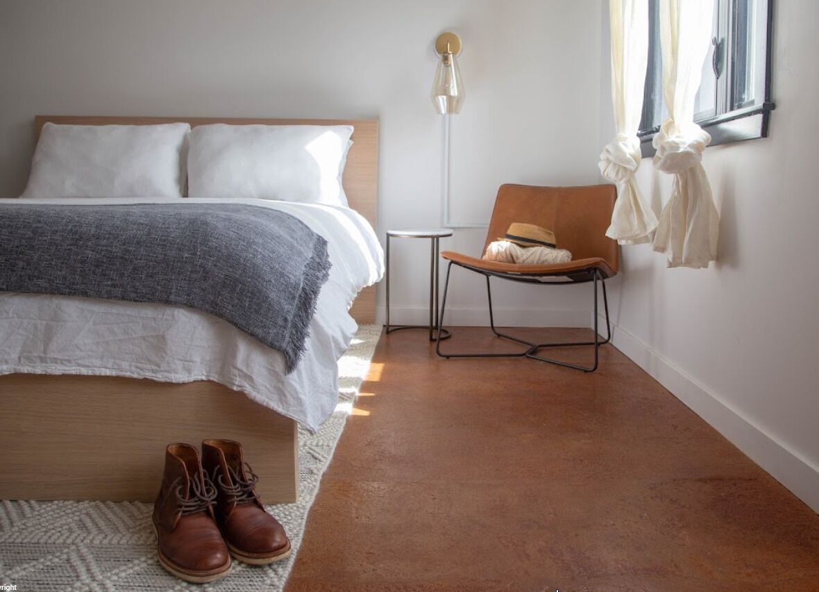 Une chambre à coucher avec un lit, une chaise, une lampe sur pied et une fenêtre.