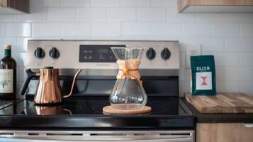 A kitchen with a stove, a glass carafe, and a coffee maker.