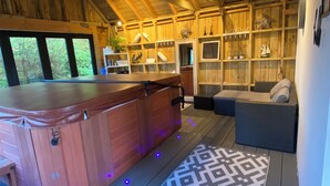 A wooden interior with a hot tub, seating area, and shelves with decorative items.