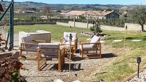 Eine Terrasse mit Gartenmöbeln, einer Pergola und Blick auf ferne Hügel.