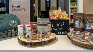Une présentation de produits et de boissons locaux, comprenant une enseigne indiquant les « spécialités de la région » et divers produits emballés.