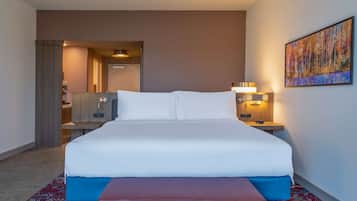Habitación de hotel con una cama grande, mesitas de noche, un cuadro en la pared y suelo cubierto de alfombra.