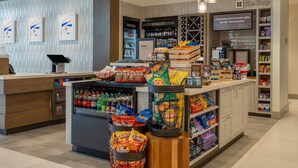 Un café avec un comptoir, des étagères remplies de collations et un présentoir réfrigéré.