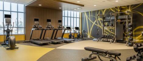A modern gym with treadmills, stationary bikes, and weightlifting equipment.