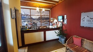 A reception area with a large window view of a harbor, a reception desk, a sofa, and a sign for HOTEL AUSTRAL.