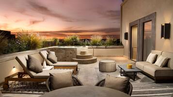 A rooftop lounge with outdoor seating, a fire pit, and a view of the sunset.