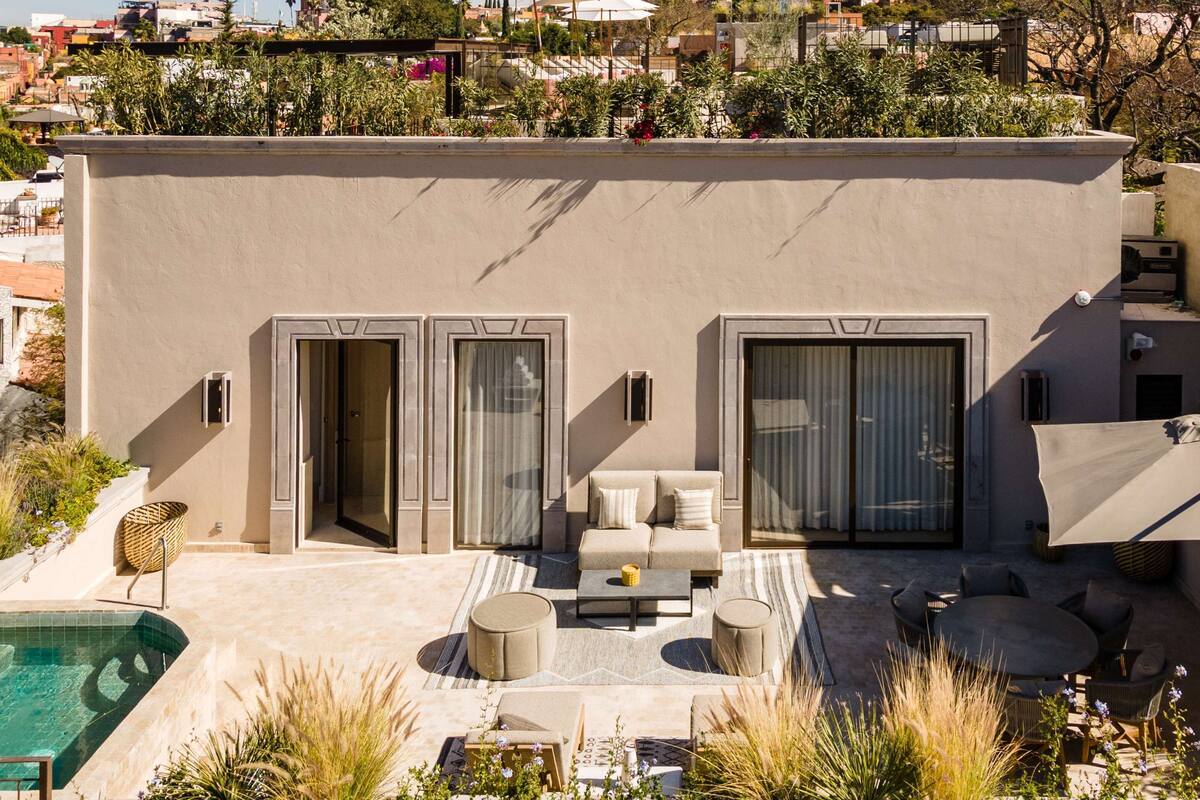 A modern building with a pool, outdoor seating, and a view of a historic cathedral in the background.