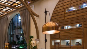 A modern lobby with a high ceiling, wooden paneling, and a central round table with chairs. - NUMU Boutique Hotel, The Unbound Collection by Hyatt (San Miguel de Allende)
