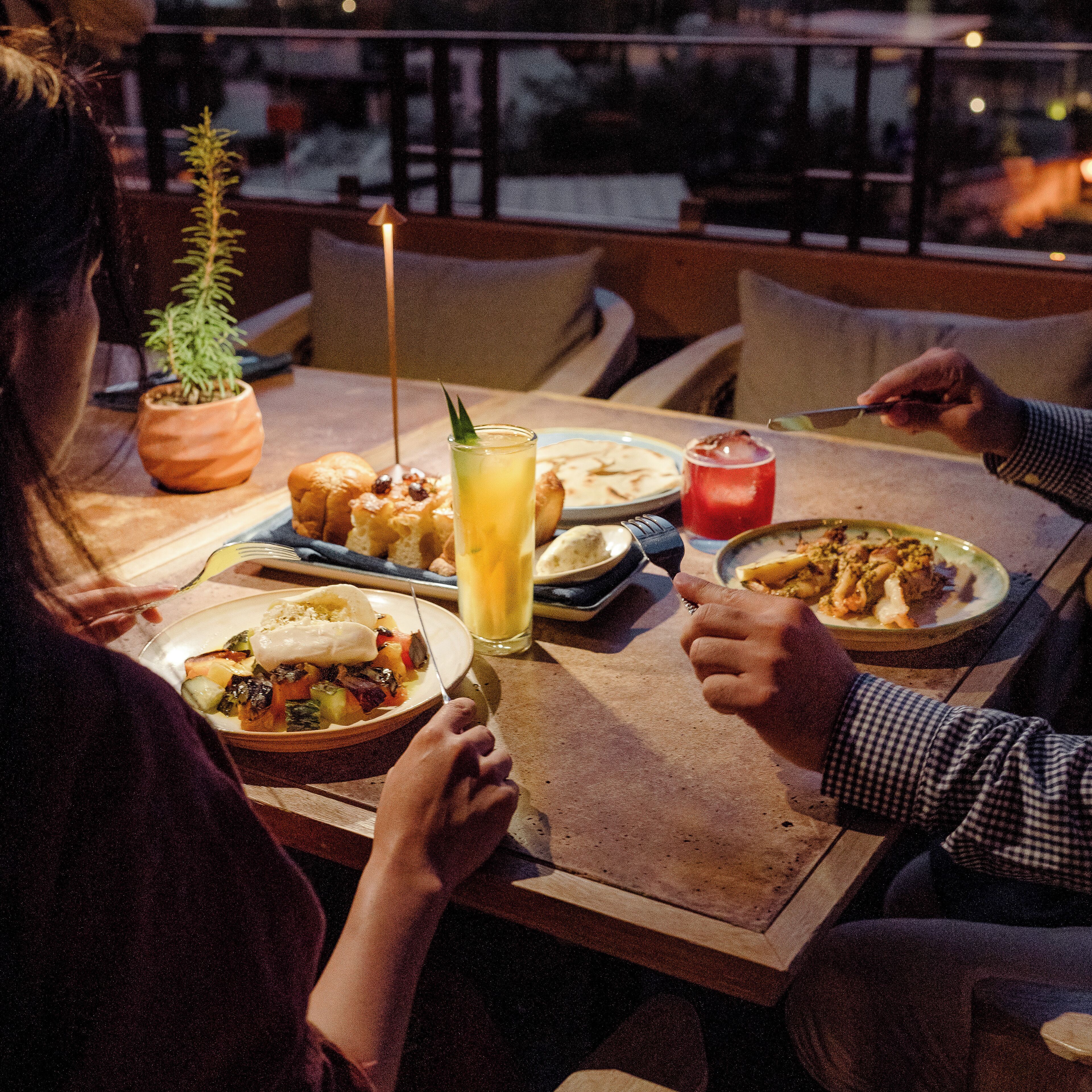 A dining table with various dishes, a candle, and a potted plant.