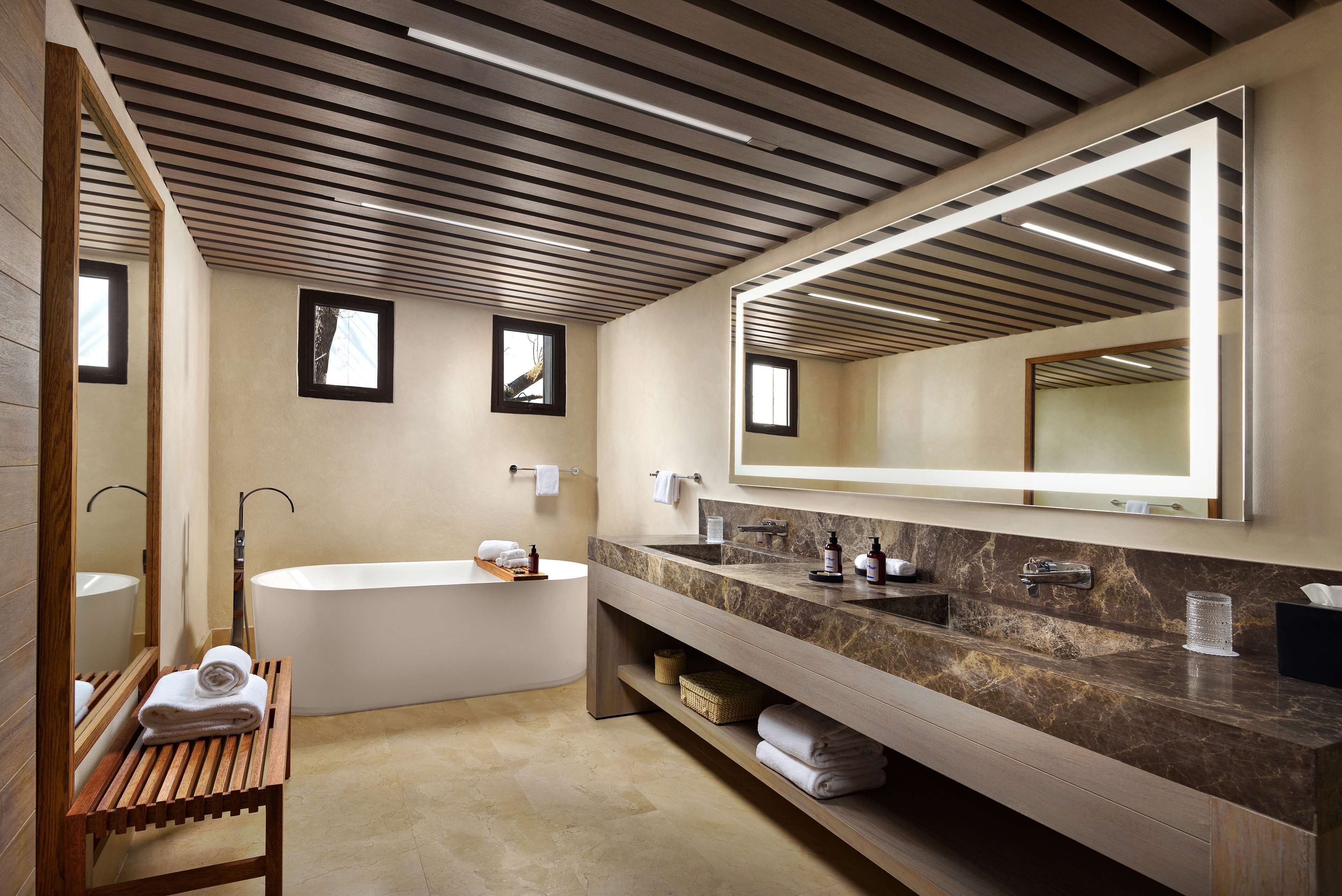A modern bathroom with a freestanding bathtub, a large mirror, and a vanity with a marble countertop.