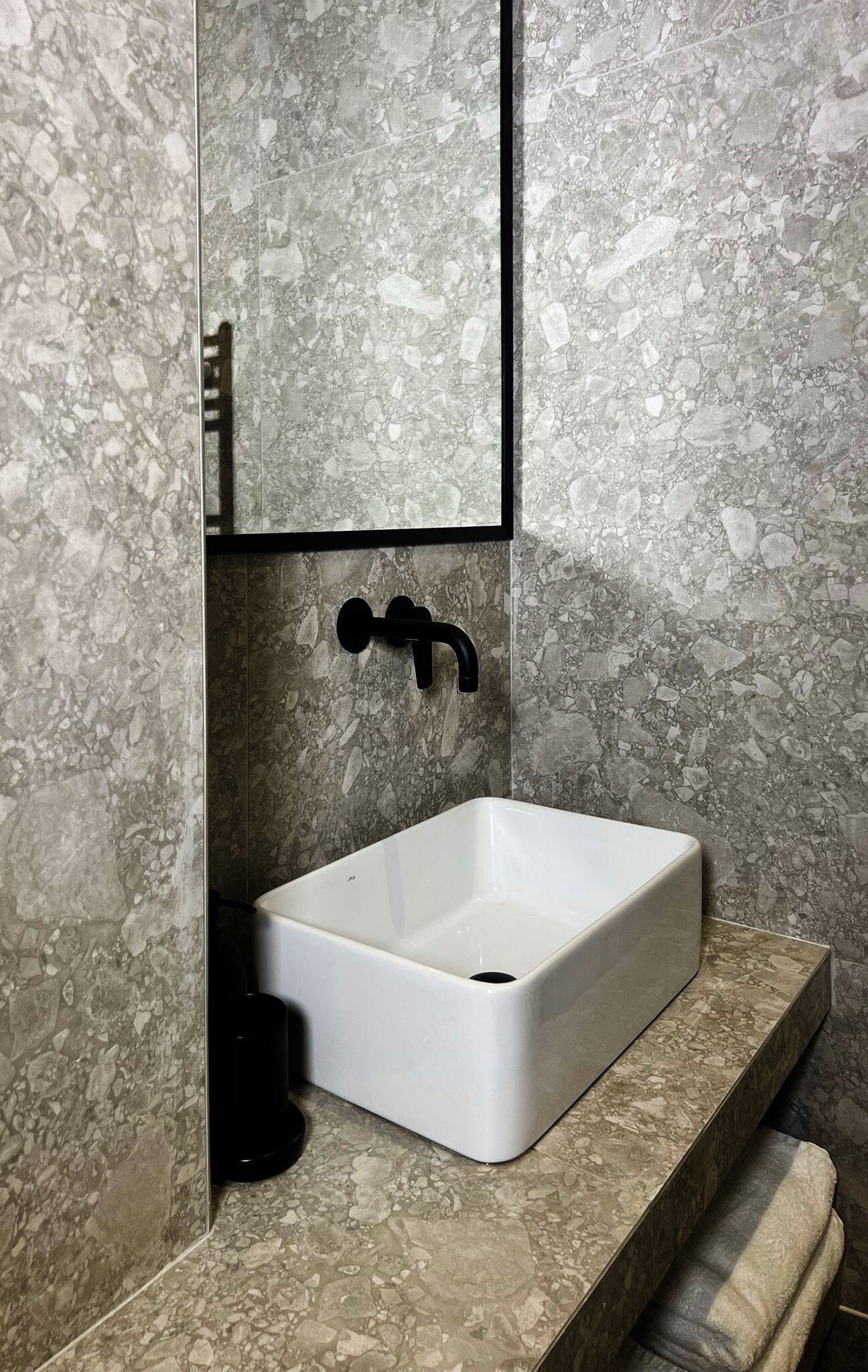 A bathroom with a white sink, black faucet, and a mirror above it.