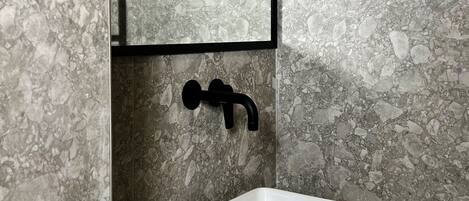 A bathroom with a white sink, black faucet, and a mirror above it.