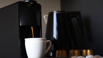 Máquina de café a servir café numa chávena, com uma pilha de cápsulas de café ao fundo.