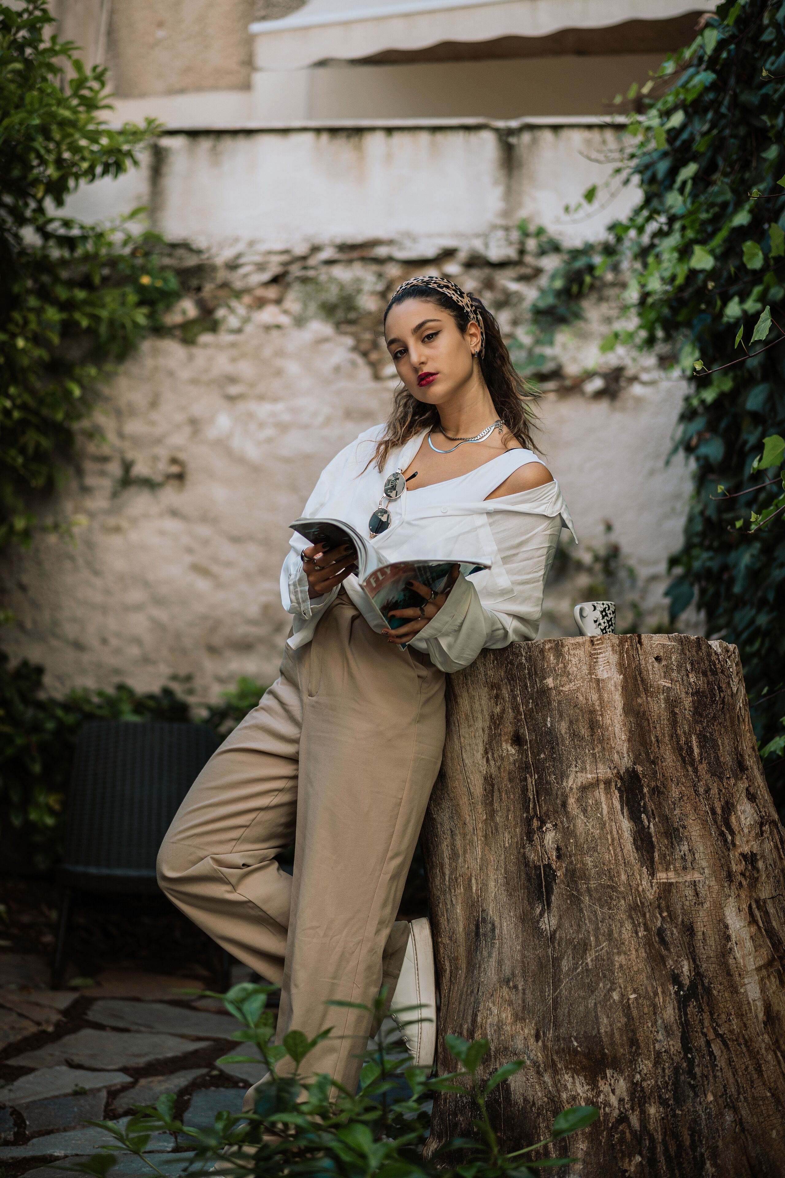 A person leaning on a wooden post, reading a magazine.