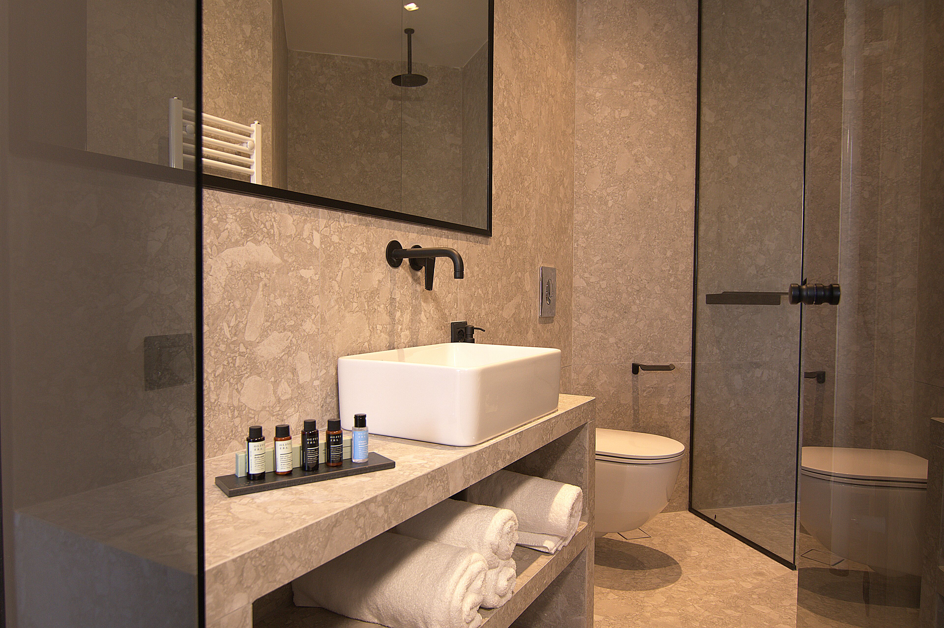 A modern bathroom with a large mirror, a white sink, and a glass-enclosed shower.