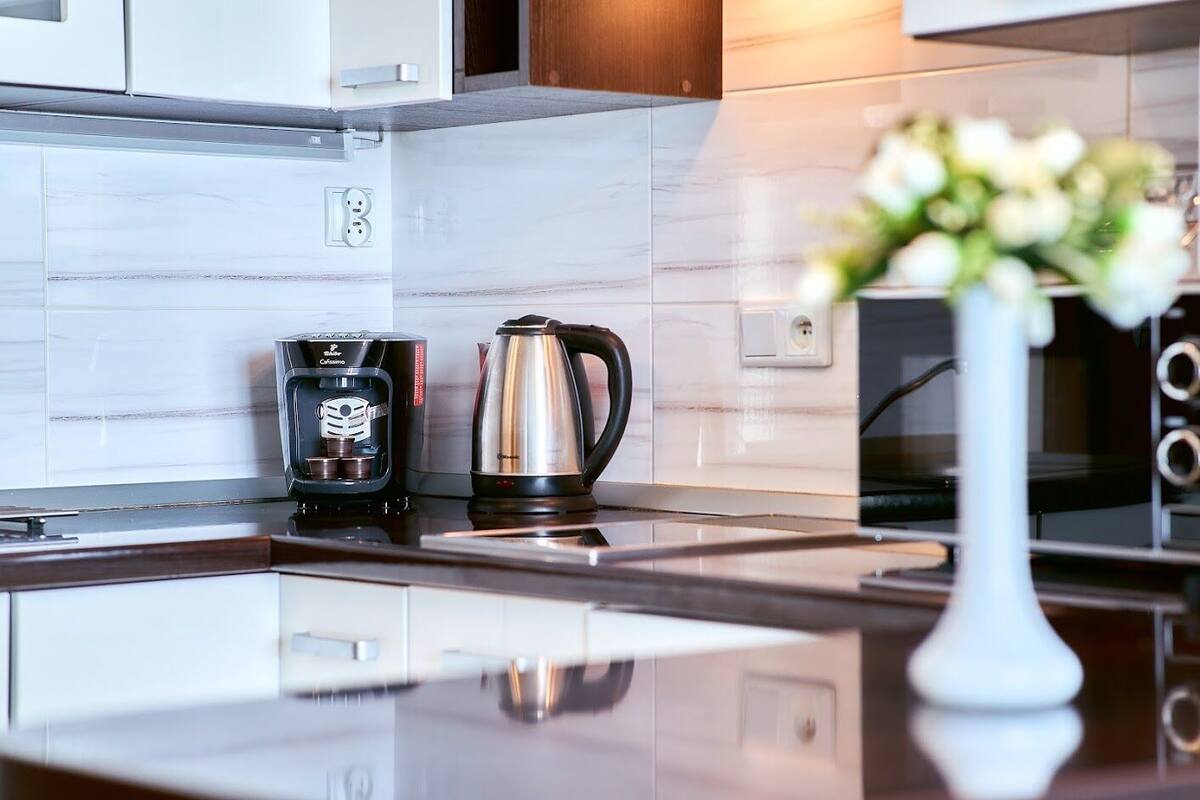Eine moderne Küche mit Kaffeemaschine, Wasserkocher und einer Vase mit Blumen auf der Arbeitsfläche.