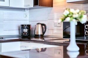 A modern kitchen with a coffee maker, a kettle, and a vase with flowers on the counter.