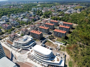 A modern urban area with a mix of residential and commercial buildings, including a distinctive curved building with a rooftop terrace.
