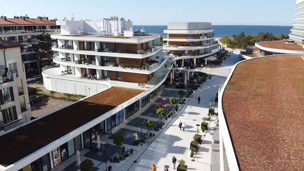 A modern multi-story hotel with a rooftop terrace and a view of the sea.