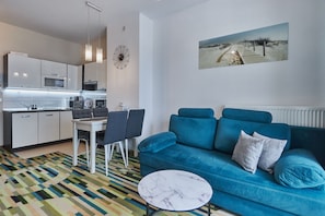 A modern apartment with a kitchen, a blue sofa, and a dining area.