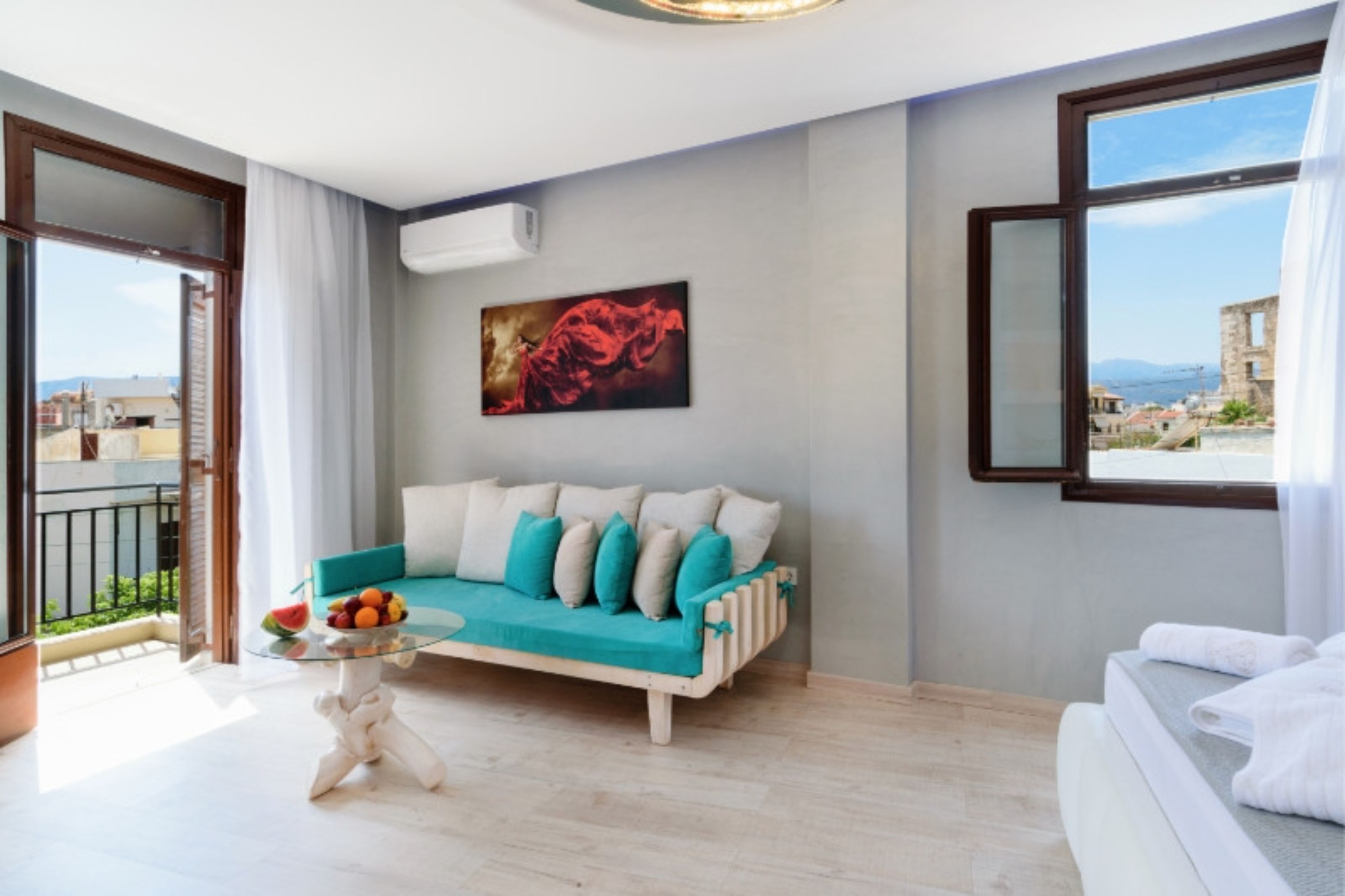 Una habitación de hotel moderna con balcón, un sofá, una mesita con fruta y una cama.