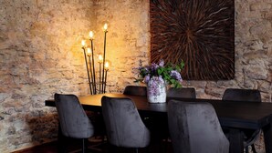 Un coin repas avec un mur en pierre, une table en bois foncé et quatre chaises grises.
