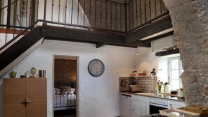 Une cuisine avec des meubles en bois, une horloge et un mur en pierre.