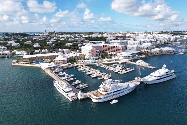 Una marina con varios yates amarrados, un hotel grande con varias construcciones, y una vista del paisaje urbano circundante.