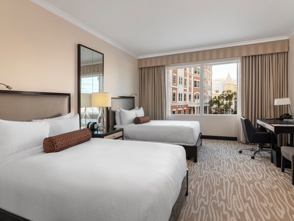 A hotel room with two beds, a desk, a chair, a lamp, and a large window with curtains. - Hamilton Princess - Fairmont Gold Experience (Pembroke Parish)
