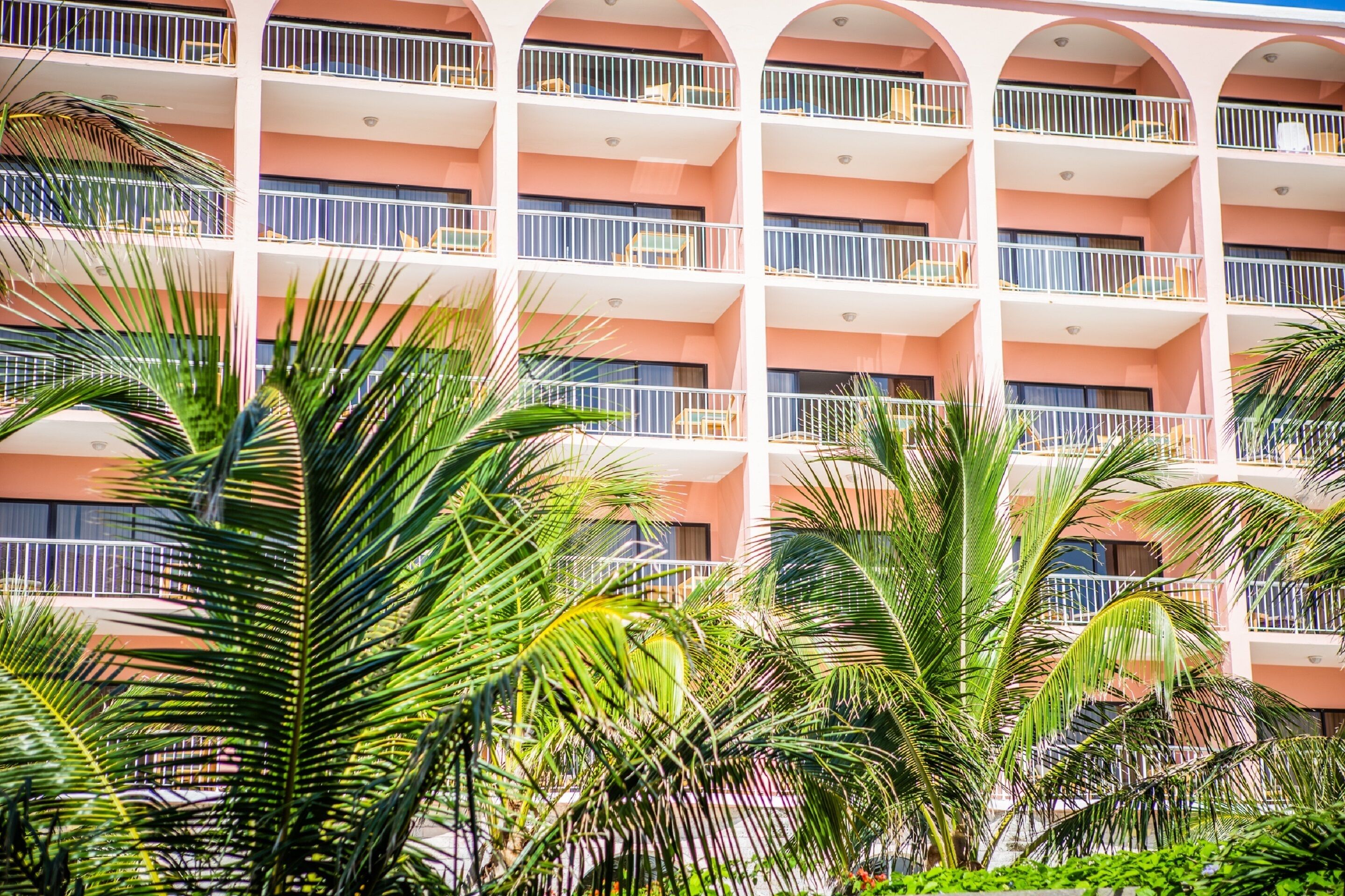 A multi-story hotel with balconies and palm trees.