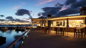 A waterfront bar with outdoor seating, a pool, and a view of the water. - Hamilton Princess - Fairmont Gold Experience (Pembroke Parish)