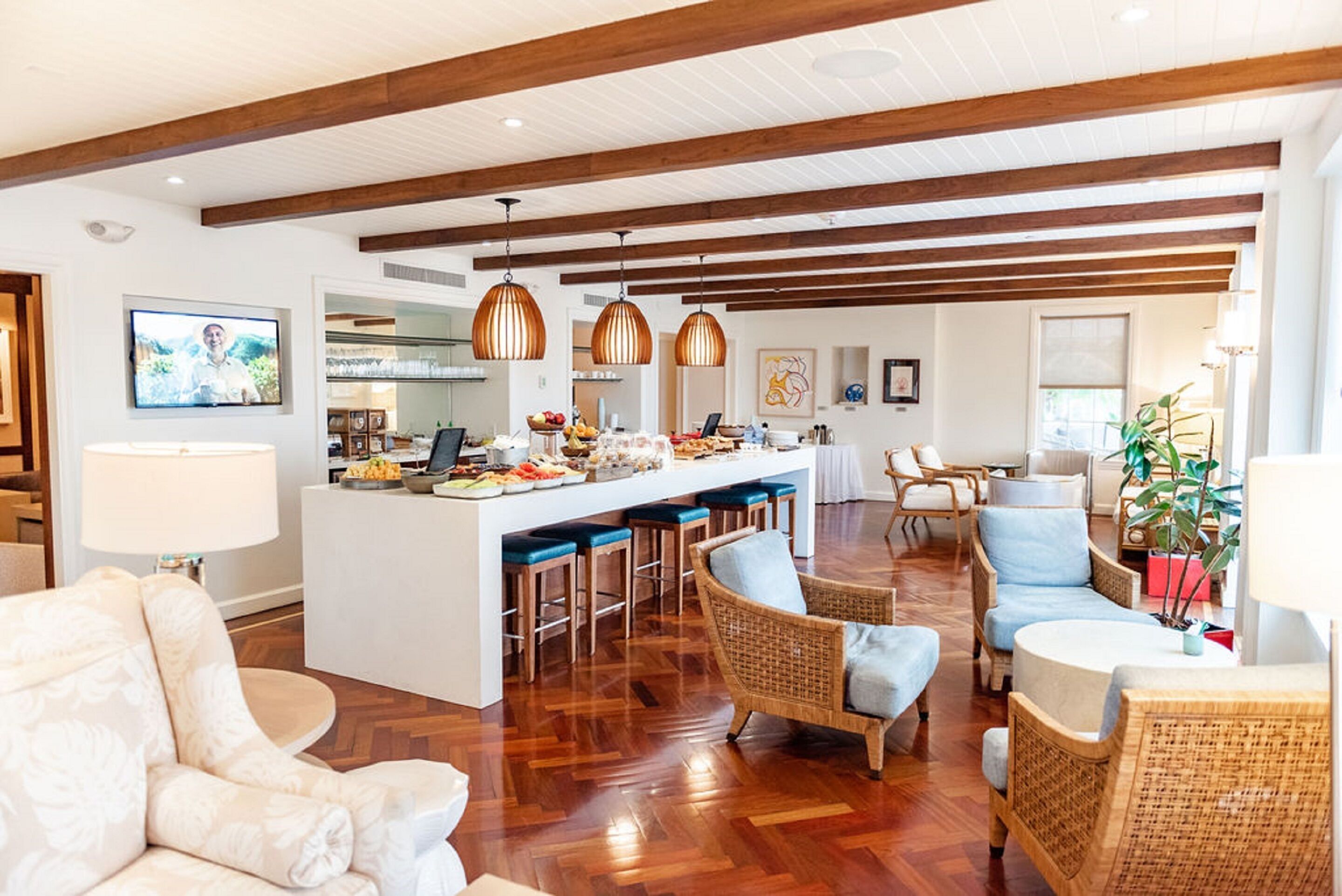 Un amplio espacio habitable con una isla central, muebles de mimbre y una cocina al fondo.