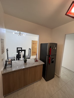 A modern kitchen with a built-in refrigerator, wooden cabinets, and a granite countertop.