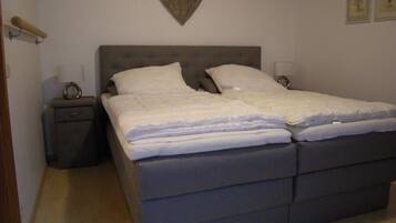 Ein Schlafzimmer mit einem Doppelbett, zwei Nachttischen, einer Wanddekoration in Herzform und einem kleinen Beistelltisch.