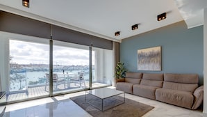 Een moderne woonkamer met een grote glazen deur die uitkomt op een balkon met uitzicht op een jachthaven.