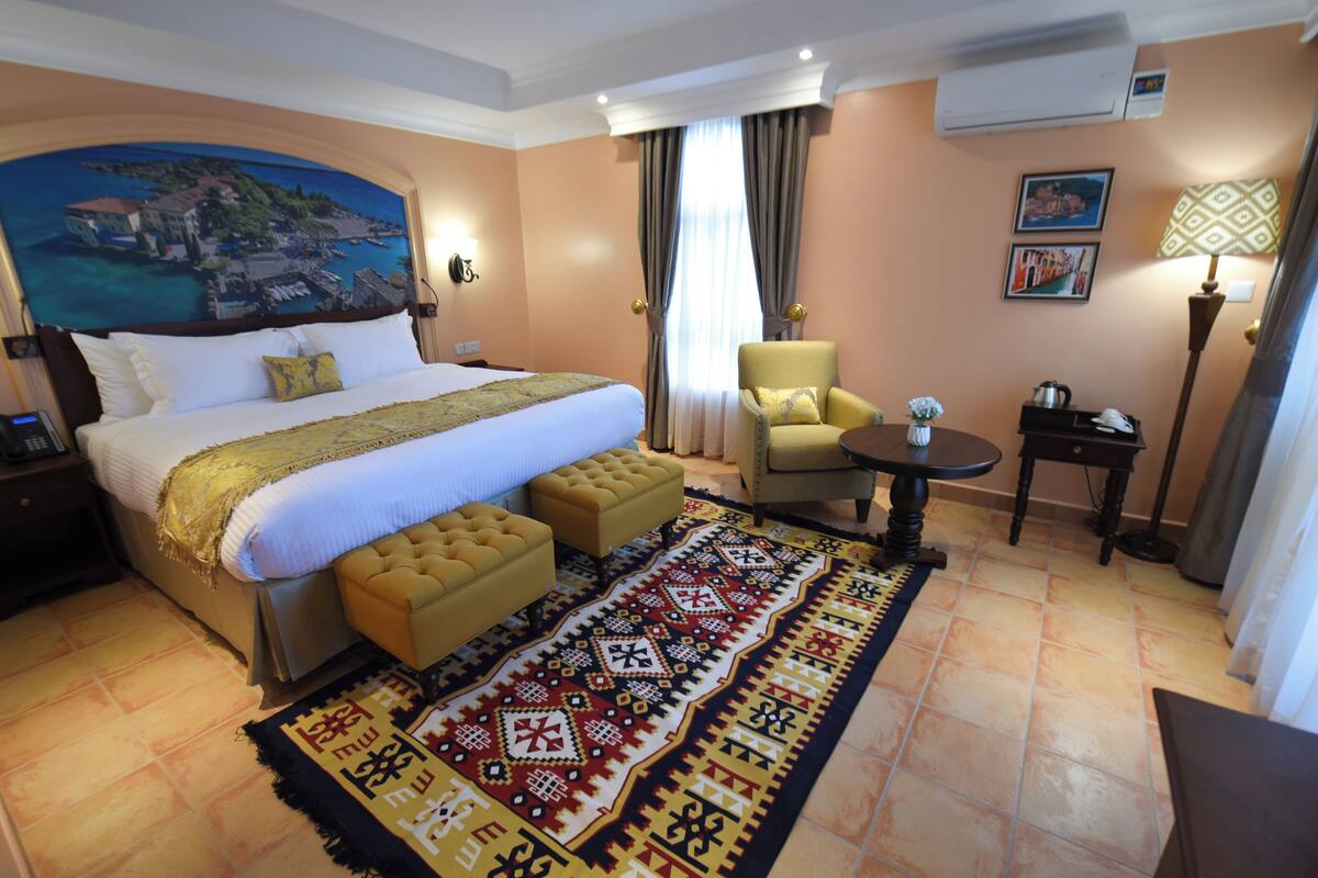 Una habitación de hotel con una cama grande, una silla, una mesita y un tapete decorativo.