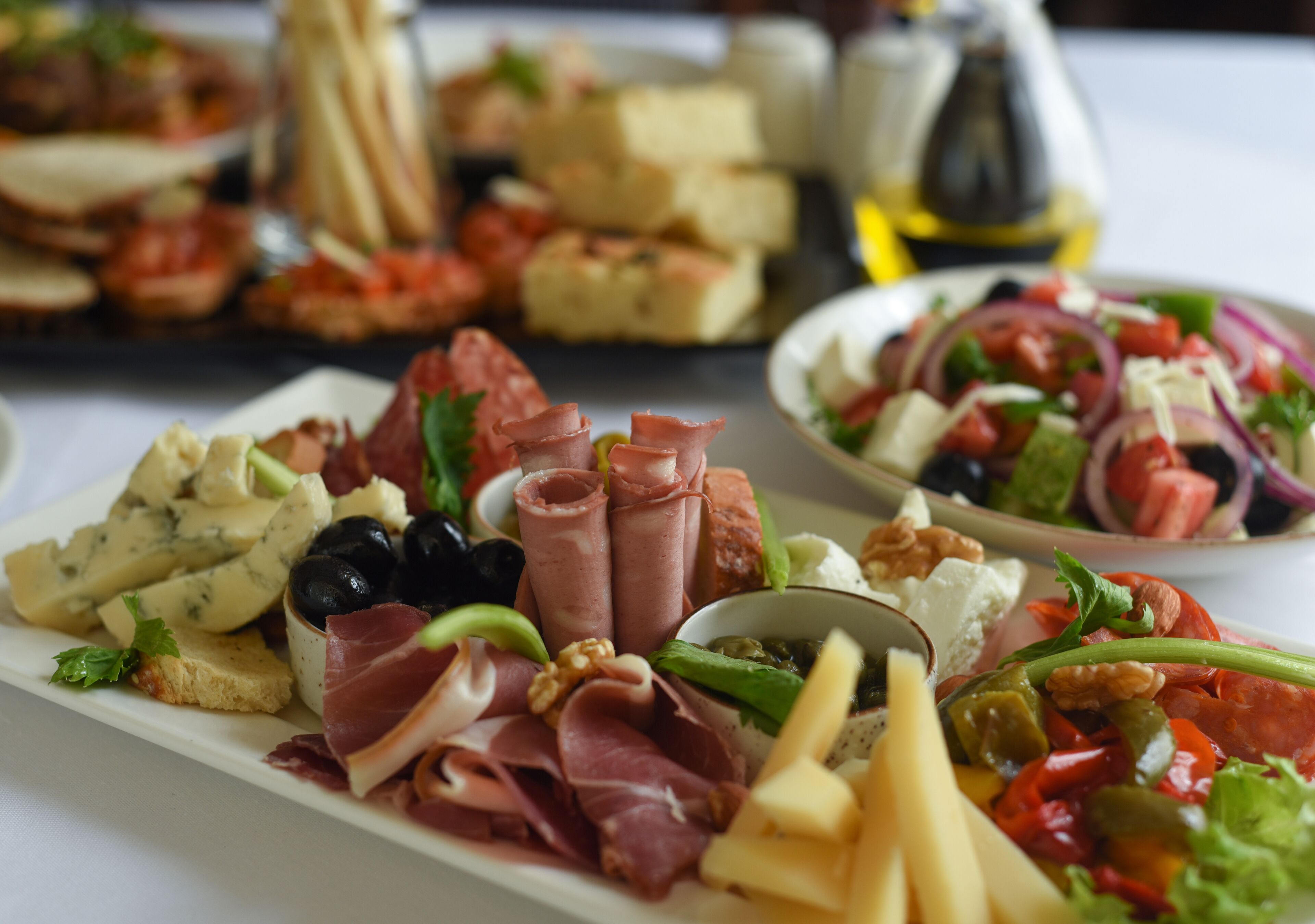 A variety of cheeses, cured meats, and vegetables on a platter.