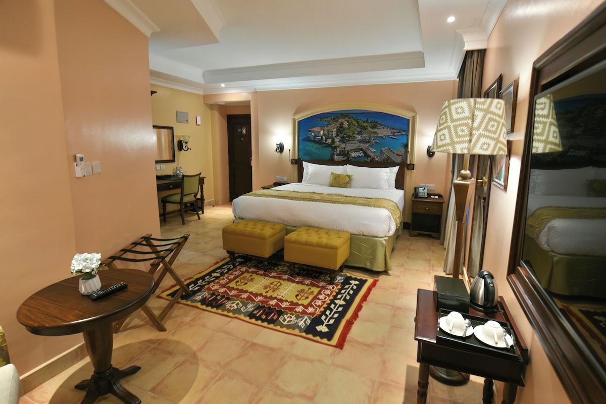 Ein Hotelzimmer mit Bett, Schreibtisch, Stuhl, Tisch und einer Kaffeestation.