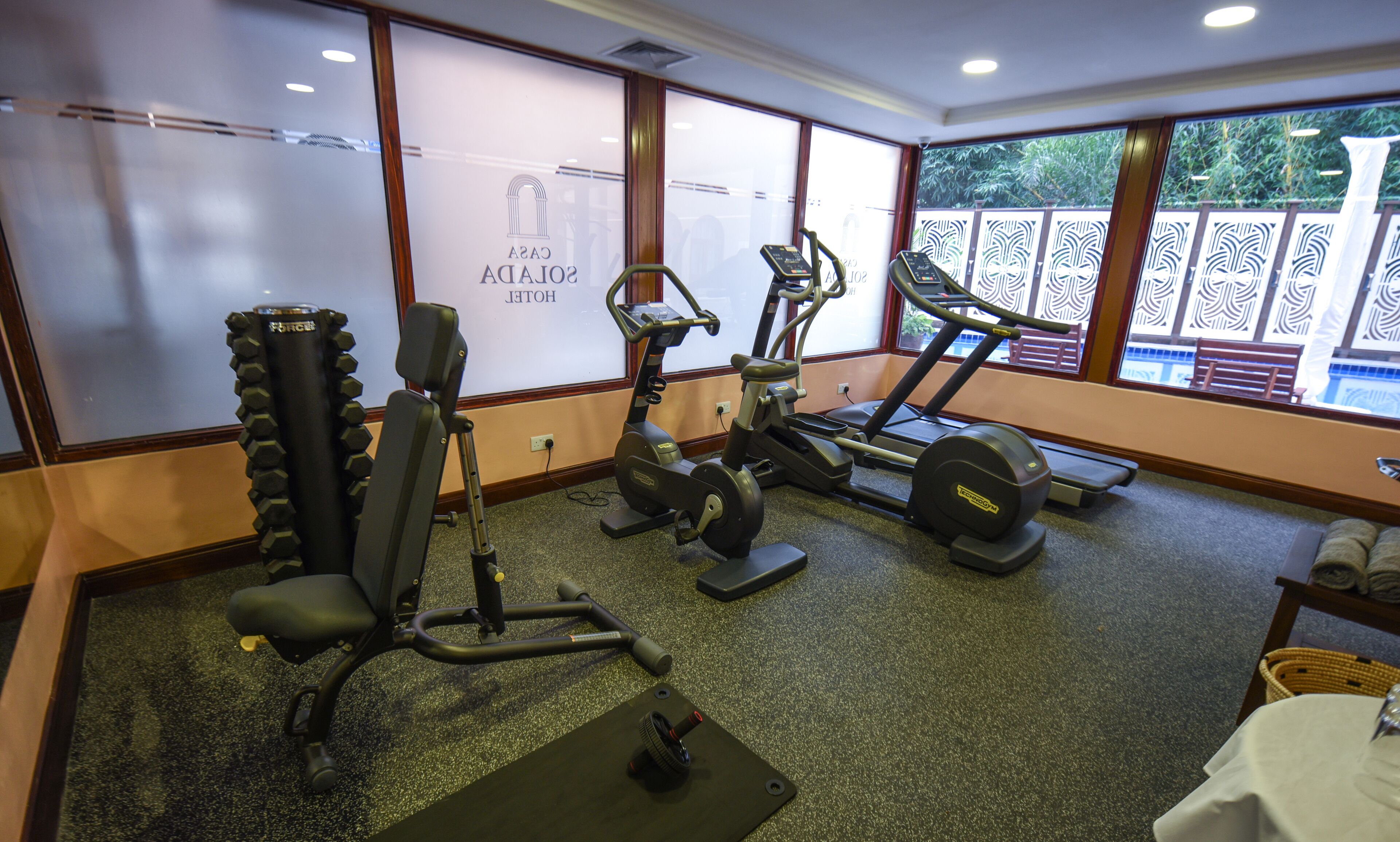 Une salle de sport équipée de divers appareils d’exercice, notamment un banc de développé couché, un vélo elliptique et un tapis de course.