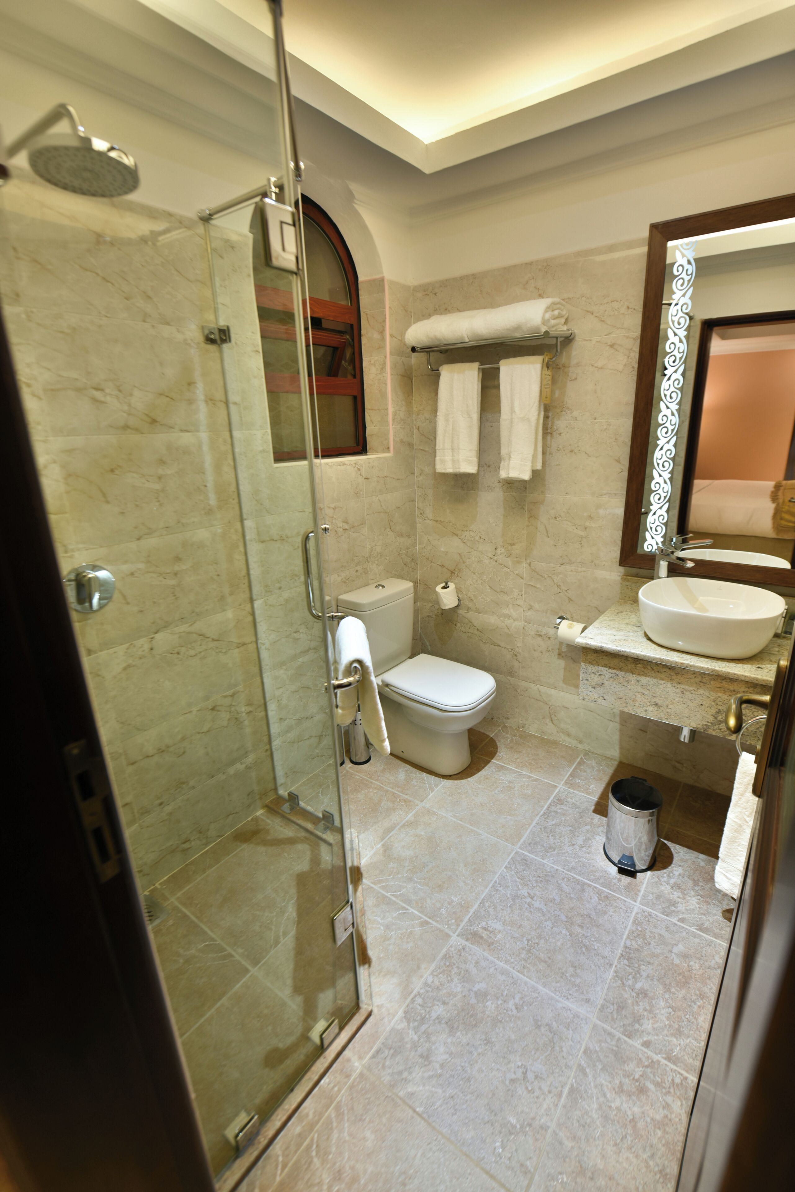 A bathroom with a glass-enclosed shower, a toilet, a sink, and a mirror.