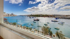 Un puerto deportivo con barcos, cielo despejado y un paisaje urbano al fondo.