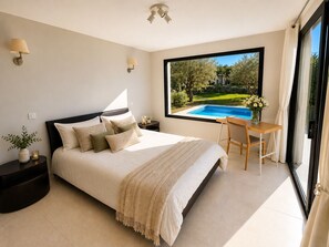 A bedroom with a large window, a bed, a nightstand, a table, and a chair. - La casa du Lez (Montferrier-sur-Lez)