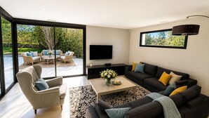 Ein modernes Wohnzimmer mit großem Fernseher, dunklen Sofas und einem Couchtisch.