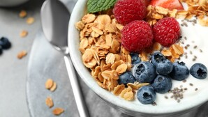 A bowl of yogurt with granola, raspberries, blueberries, and a mint leaf. - Beach Bay Hvar Hotel (Hvar)