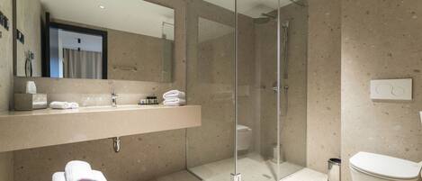A modern bathroom with a glass-enclosed shower, a large mirror, and a vanity with a sink and towel stack.